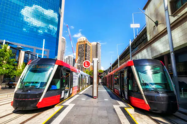 Two light rail tram trains at Circuar Quay end stop in Sydney city CBD on a sunny day - modern urban eco transport.