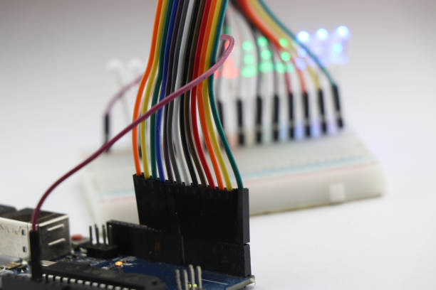 istock Set of jumper wires connected to a microcontroller board that completes the circuit with Breadboard and LED showing prototyping electronic projects concept 1360154596
