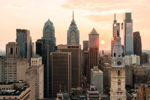 Aerial panoramic cityscape of Philadelphia financial downtown, Pennsylvania, USA. Philadelphia City Hall Clock Tower at sunset golden hour. A vibrant business and cultural neighborhoods.