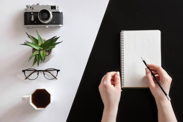 istock Flat lay composition with hands and blank notepad on black and white background. 1360156886