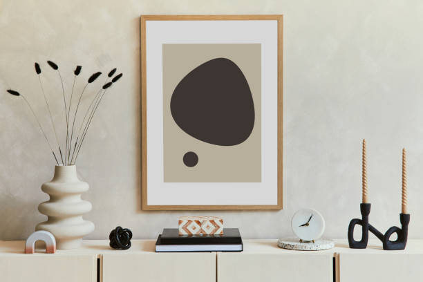 istock Stylish and modern beige living room interior composition with mock up poster frame, beige wooden sideboard and boho inspired accessories. Template.