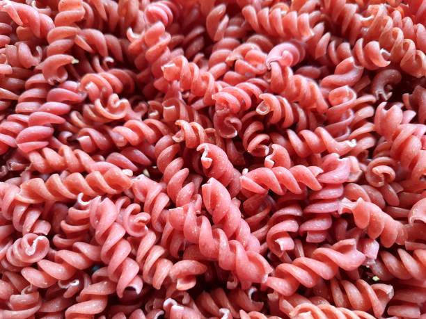 istock Background texture and pattern of egg noodles and beetroot on a spiral spaghetti screw or noodles. in full frame. View from above. Close up. macro. 1360161651