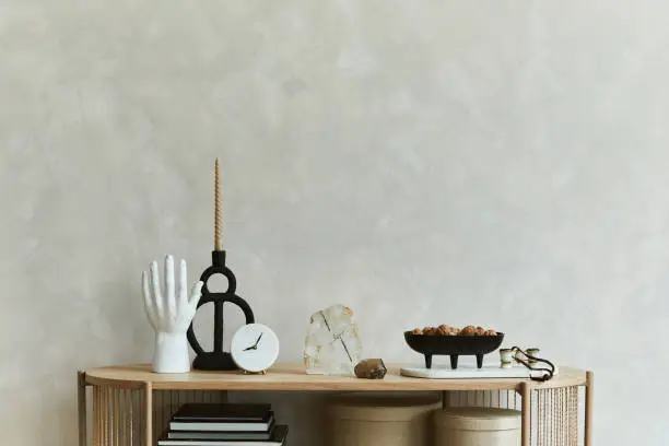 Photo of Stylish composition of personal accessories on the console in the living room. Sculpture, candlectick, minerals and tray. Copy space. Template.