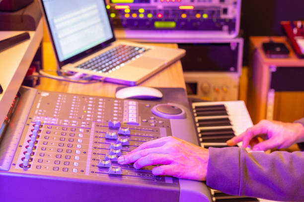 istock sound engineer, producer, composer hands mixing audio track on control surface mixer while playing keyboard for recording midi track on laptop computer. music production concept 1360164705