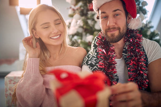 istock A young guy is posing for a photo with his girlfriend and with a christmas present he got from her. Christmas, home, relationship, presents 1360168647
