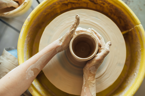 Hands of a potter. Potter making ceramic pot on the pottery wheel.