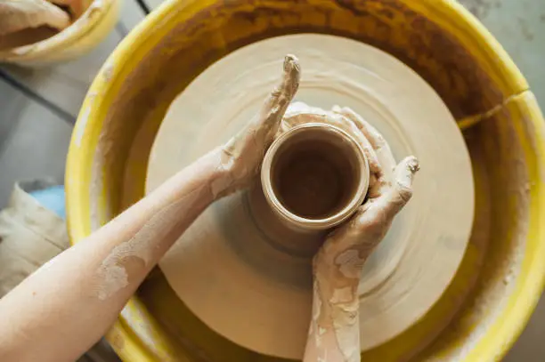 Photo of Hands of a potter. Potter making ceramic pot on the pottery wheel