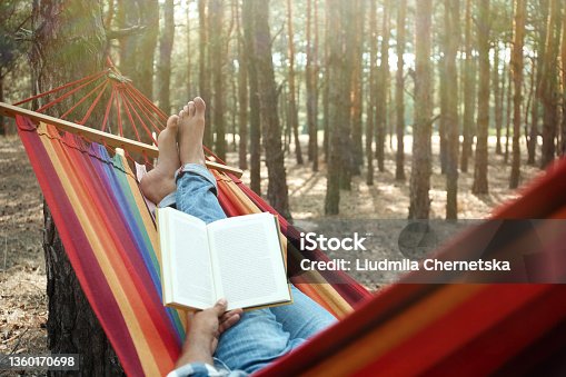 istock Man with book relaxing in hammock outdoors on summer day, closeup 1360170698