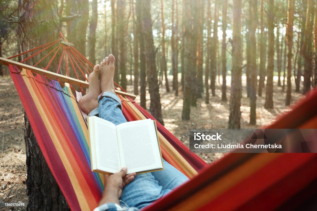Man with book relaxing in hammock outdoors on summer day, closeup Relaxation Stock Photo