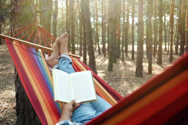 homem com livro relaxando em rede ao ar livre no dia do verão, close-up - resting relaxation book break - fotografias e filmes do acervo