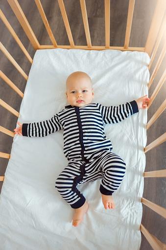 Cute baby in wooden bed, top view