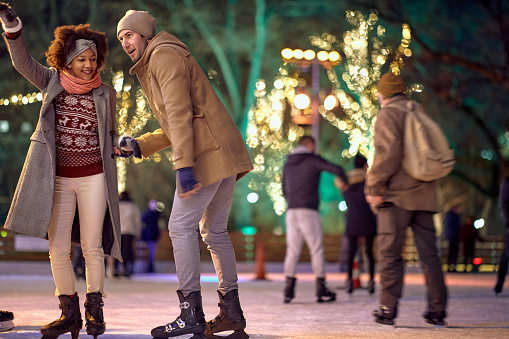 Carefree multiethnic couple enjoying night ice skating together