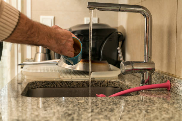 istock Man washing a cup and dishes in the kitchen sink. 1360171933