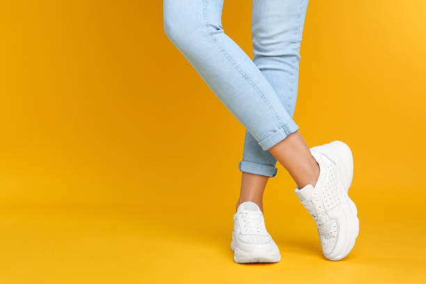 Woman wearing stylish sneakers on yellow background, closeup. Space for text Woman wearing stylish sneakers on yellow background, closeup. Space for text yellow shoes stock pictures, royalty-free photos & images