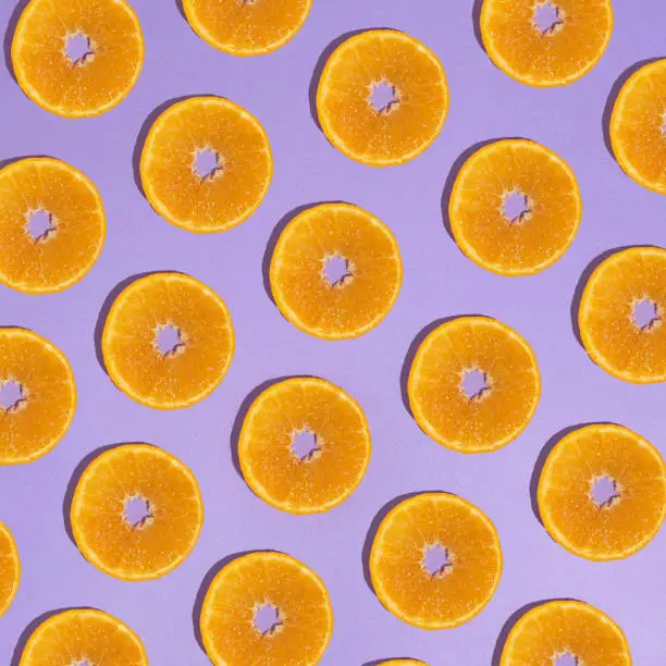 orange fruit circles in a row on a purple background.pattern aesthetic design concept idea