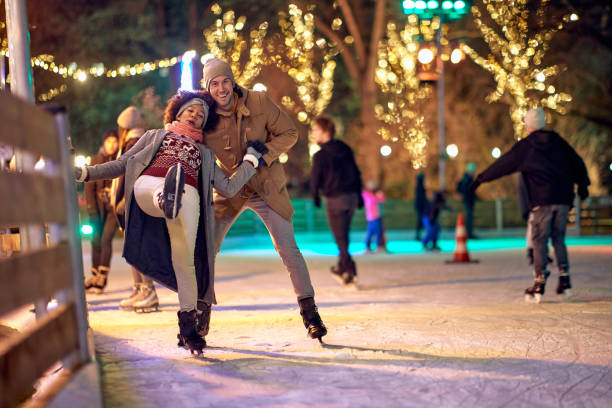 istock A young guy is helping his girlfriend while learning to skate at ice-skating rink during christmas holidays in the city. Christmas, New Year, holiday, love 1360173883