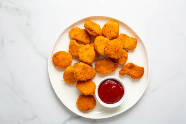 Chicken nuggets and ketchup from above on white plate