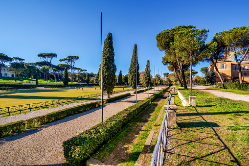 A suggestive and quiet autumnal view of the hippodrome of Piazza di Siena, in the green heart of Villa Borgese. In this space, built by the Borghese family in honor of the Tuscan city of Siena at the end of the 18th century, the International Horse Competition of Rome has been held since 1926. On the right the Casetta dell'Orologio, the former residence of the Borghese family gardeners and current country house for horse racing events. Considered the green lung of Rome, Villa Borghese is the largest public park in the city with almost 80 hectares of extension, where residents and tourists can spend hours of relaxation and silence among tree-lined avenues, ponds and Italian and English-style gardens surrounded by trees and ancient pines. The area of the Villa Borghese includes the extension of ancient gardens the of the Borghese family since 1580, while the current arrangement of the park was completed in 1903 in neoclassical style. In 1980 the historic center of Rome was declared a World Heritage Site by Unesco. Super wide angle image in high definition format.