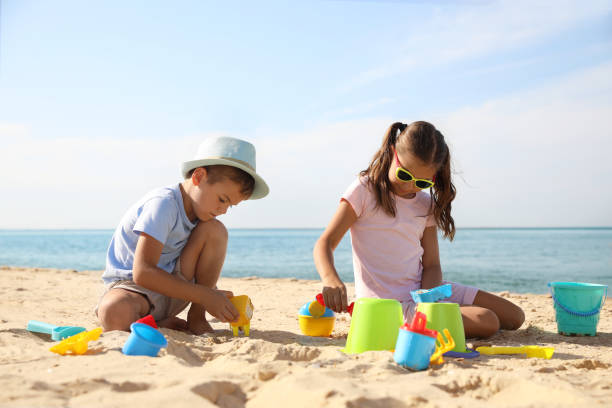 Cute little children playing with plastic toys on sandy beach Cute little children playing with plastic toys on sandy beach children at the beach stock pictures, royalty-free photos & images