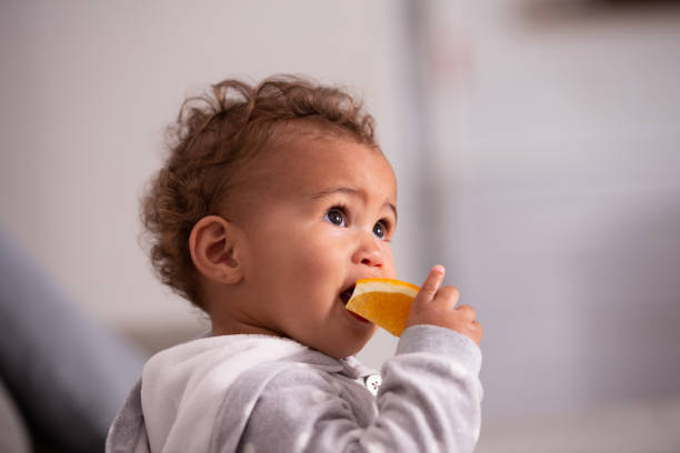 istock Baby eating orange fruit. 1360179812