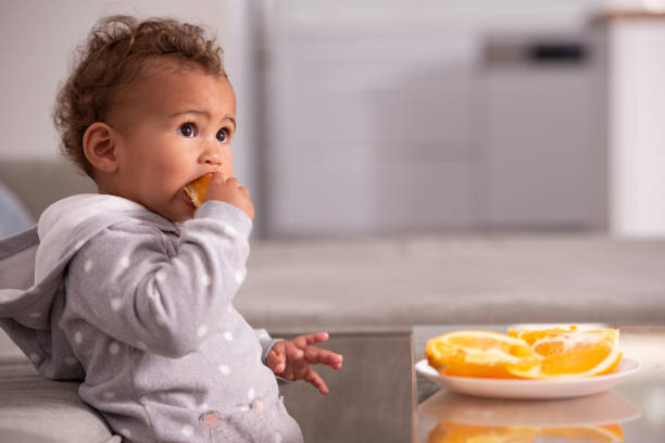istock Baby eating orange fruit. 1360179986