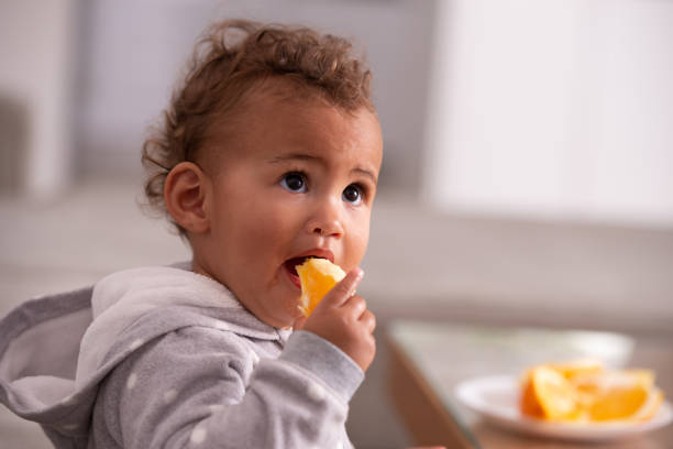 istock Baby eating orange fruit. 1360179994