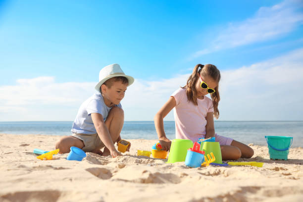 istock Cute little children playing with plastic toys on sandy beach 1360180061