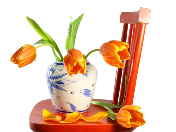 tulips in a decorative vase illuminated by vibrant purple light painting on a dark wooden surface.