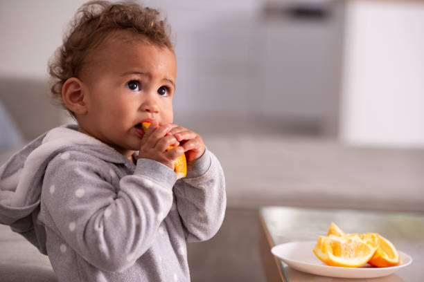 istock Baby eating orange fruit. 1360180279