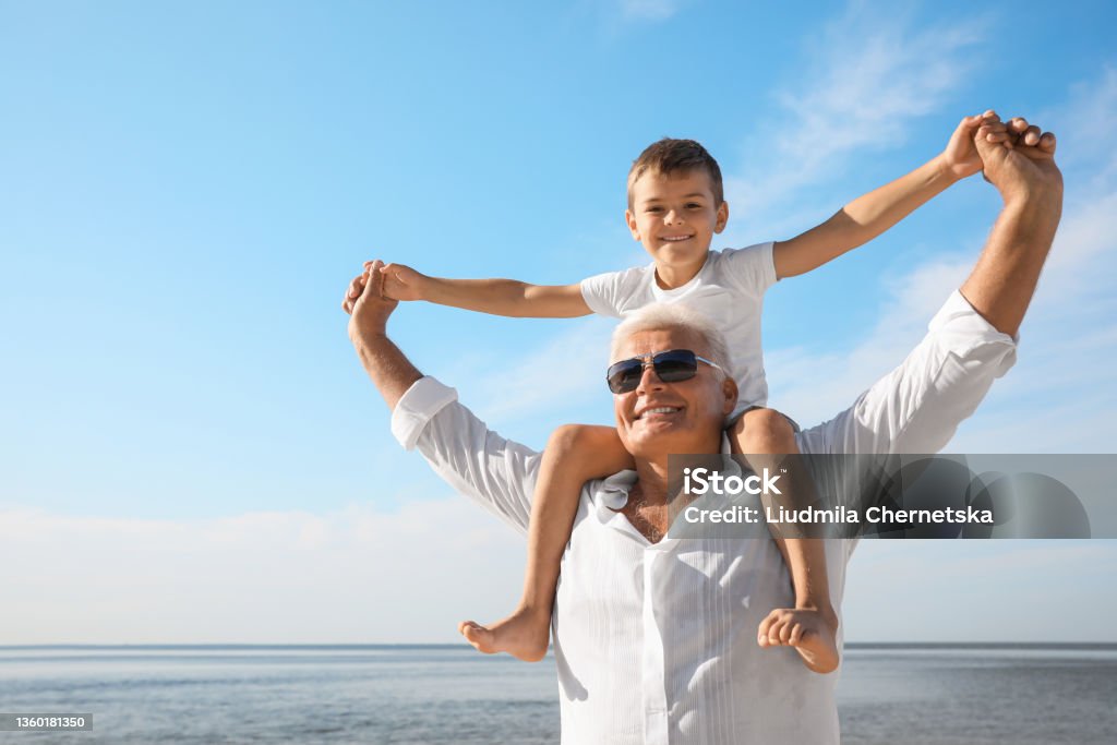 Cute little boy with grandfather spending time together near sea Grandfather Stock Photo