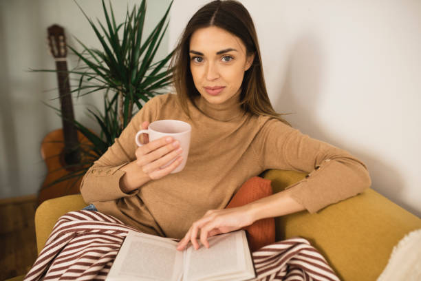istock Woman relaxing on the sofa with coffee and book 1360182936