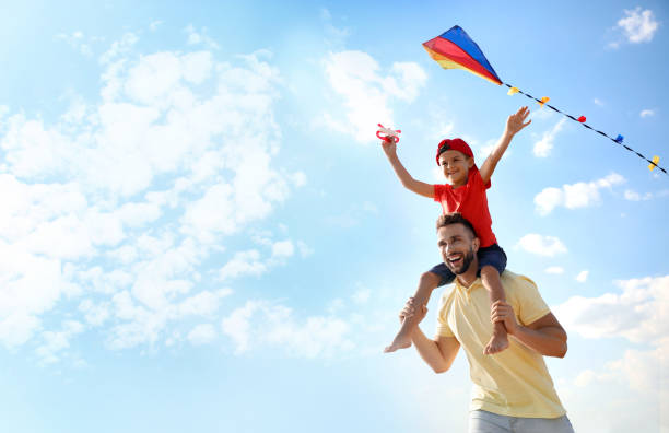 padre felice e il suo bambino che giocano con l'aquilone in una giornata di sole. trascorrere del tempo nella natura - fun time foto e immagini stock