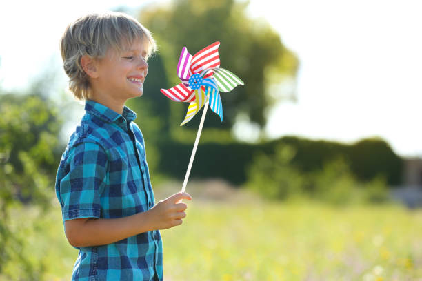 istock Cute little boy with pinwheel outdoors, space for text. Child spending time in nature 1360187164