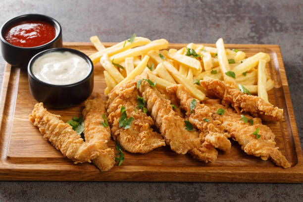 strisce di pollo fritte croccanti con salse e patatine fritte in primo piano sul vassoio di legno. orizzontale - chicken tender foto e immagini stock