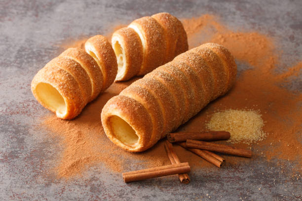 Trdelník Czech is a kind of spit cake it is made from rolled dough that is wrapped around a stick, then grilled and topped with sugar and cinnamon close up. Horizontal Trdelník Czech is a kind of spit cake it is made from rolled dough that is wrapped around a stick, then grilled and topped with sugar and cinnamon close up on the table. Horizontal trdelník stock pictures, royalty-free photos & images
