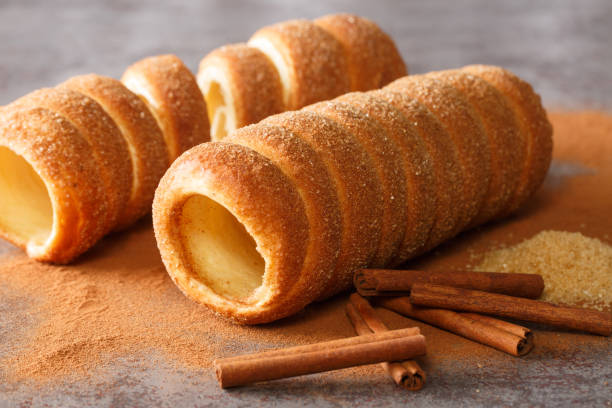 Trdelnik is a traditional sweet cake made from yeast dough held around a stick, then fried and sprinkled with sugar and cinnamon close up. Horizontal Trdelnik is a traditional sweet cake made from yeast dough held around a stick, then fried and sprinkled with sugar and cinnamon close up on the table. Horizontal trdelník stock pictures, royalty-free photos & images