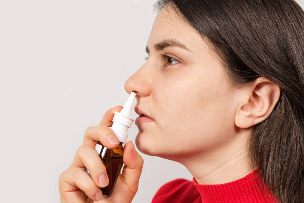 A female patient shoves a spray into the nose to treat rhinitis, an allergy with difficulty breathing. Copy text space. A female patient shoves a spray into the nose to treat rhinitis, an allergy with difficulty breathing. Copy text space saline drip stock pictures, royalty-free photos & images