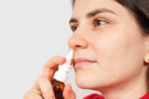 A female patient shoves a spray into the nose to treat rhinitis, an allergy with difficulty breathing. Copy text space. A female patient shoves a spray into the nose to treat rhinitis, an allergy with difficulty breathing. Copy text space saline drip stock pictures, royalty-free photos & images