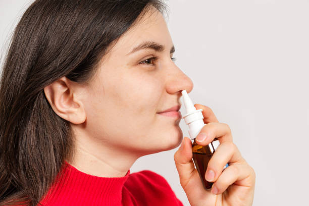 A female patient shoves a spray into the nose to treat rhinitis, an allergy with difficulty breathing. Copy text space. A female patient shoves a spray into the nose to treat rhinitis, an allergy with difficulty breathing. Copy text space saline drip stock pictures, royalty-free photos & images