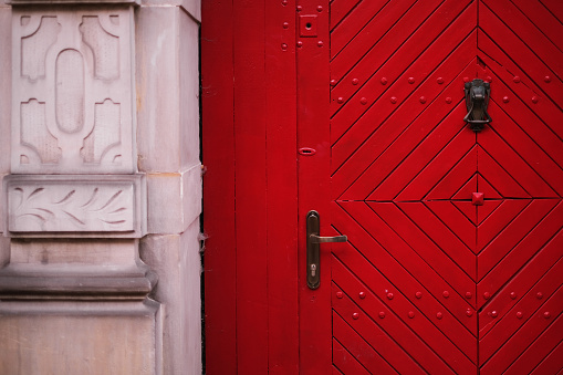 closed wooden red door in a beautiful old house in the city center. Door lock in wooden door exterior of vintage house