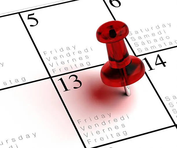 friday the 13th written onto a multilingual calendar with a red thumbtack with transparency