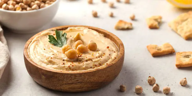 Photo of Banner hummus of their chickpeas in a wooden plate. Vegetarian food