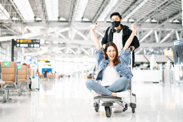 New Normal and travel bubble concept.happy attractive Young Asian tourist couple excited together for the trip female sitting and cheering on baggage trolley or luggage trolley in airport New Normal and travel bubble concept.happy attractive Young Asian tourist couple excited together for the trip female sitting and cheering on baggage trolley or luggage trolley in airport irish travellers photos stock pictures, royalty-free photos & images