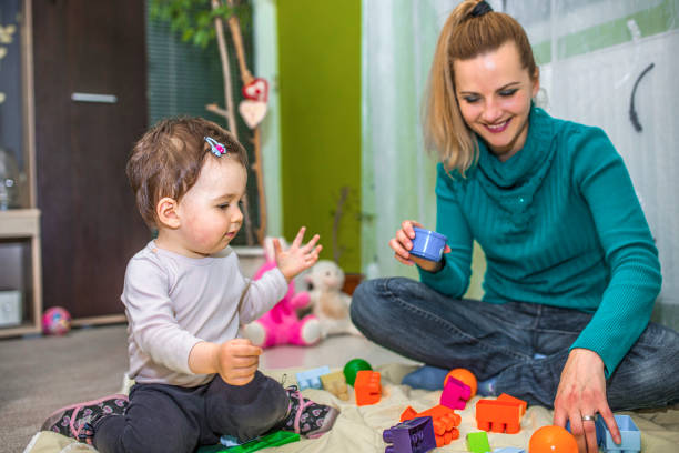 istock Happy mother playing with her daughter on the floor 1360199065