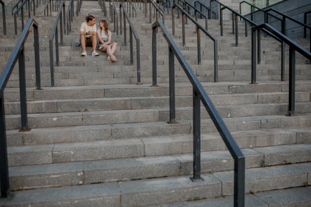 istock Charming couple is sitting on the stairs outside and having nice conversation. 1360200254