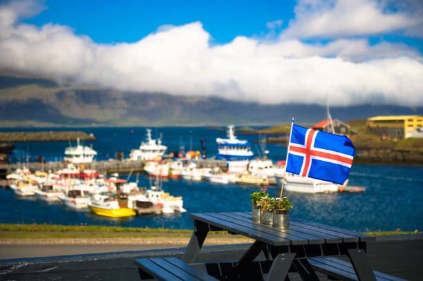 istock Flag of Iceland placed on a restaurant table with a harbor in the background 1360200645