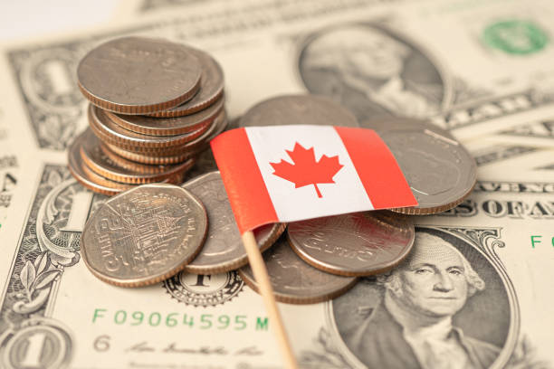 istock Stack of coins with Canada flag on dollar banknotes. 1360202698