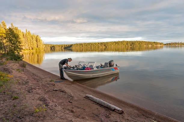 Fisherman tends to his boat on a serene lake in the northern Canada.