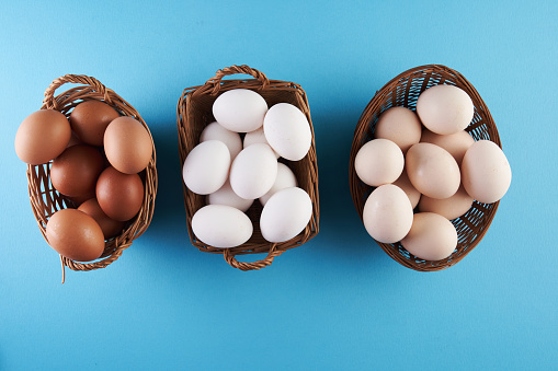 top view of three basket of egg on blue background, egg with different color shades