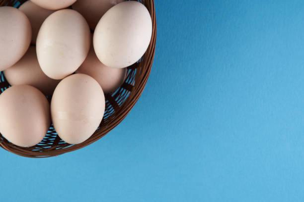 istock top view of basket of white eggs on blue background 1360207144
